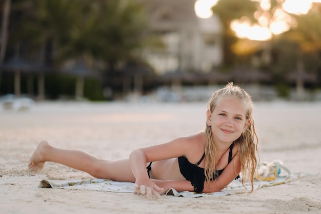 Una niña encantadora yace en la playa y dibuja en la arena. Una niña yace en la playa de la isla de Mauricio.