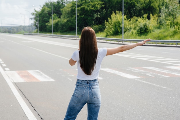 Foto una niña se encuentra cerca de un automóvil averiado en medio de la carretera y pide ayuda por teléfono mientras intenta detener a los automóviles que pasan. avería y avería del coche. esperando ayuda.