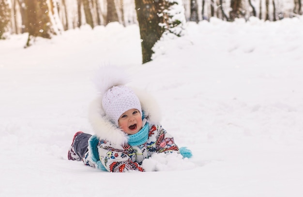 Niña se encuentra en la nieve en un día de invierno