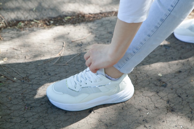 La niña endereza los cordones de los zapatos en el parque.