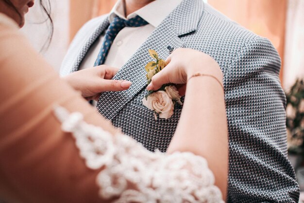 Una niña endereza una flor de boda en la chaqueta de un hombre