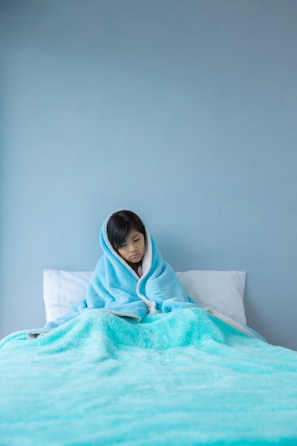 Niña enferma en la cama cubierta con mantas