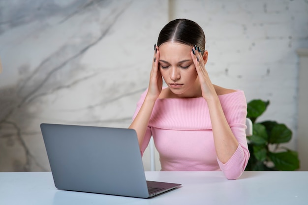 Niña enferma enferma cansada, mujer joven que sufre de dolor de cabeza, migraña trabajando en la computadora portátil