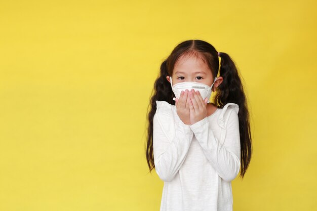 Niña enferma con máscara protectora sobre fondo amarillo