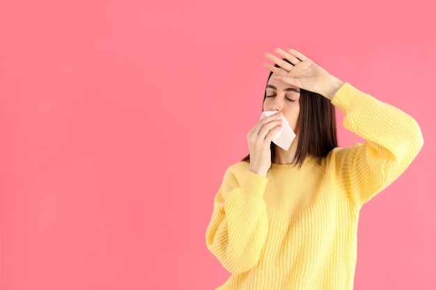 Niña enferma en un suéter amarillo sobre un fondo rosa