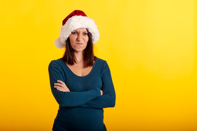 Foto una niña enojada con un sombrero de santa claus con un fondo amarillo