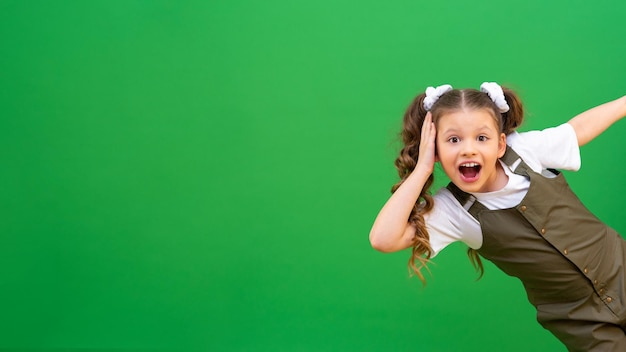 Una niña entusiasta y alegre mira desde la esquina Una hermosa niña con cabello rizado mira desde detrás del fondo