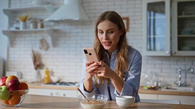 Niña enviando mensajes por teléfono móvil a casa de primer plano mujer feliz buscando pantalla de teléfono móvil