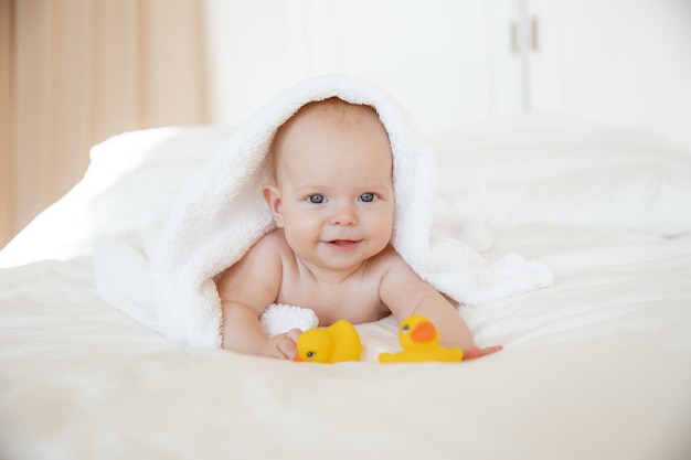 niña envuelta en una toalla acostada en el dormitorio después de bañarse