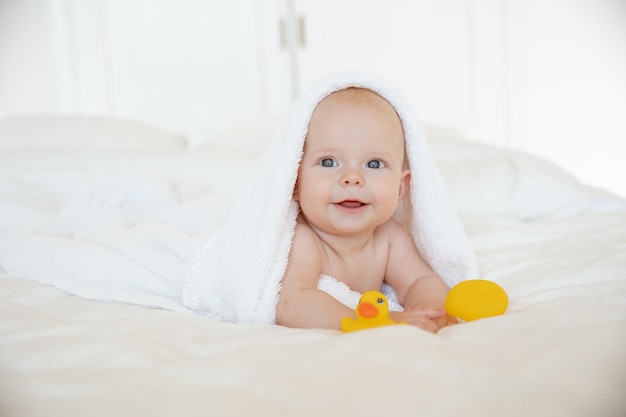 niña envuelta en una toalla acostada en el dormitorio después de bañarse