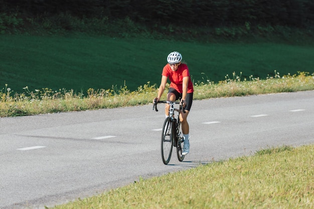Niña con equipo deportivo de carreras montando en una ruta de ciclismo de carretera abierta