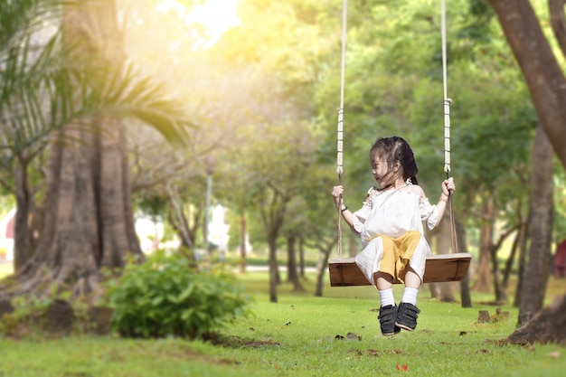 Niña es swing en verano parque verde al aire libre