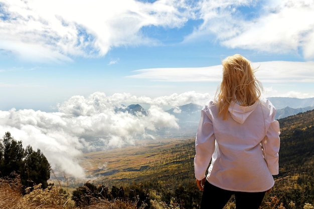 La niña es una viajera en una caminata por la montaña Una vista desde arriba de las montañas y las nubes Por encima de las nubes