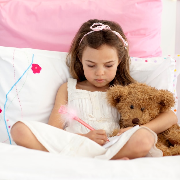 Niña escribiendo en la cama