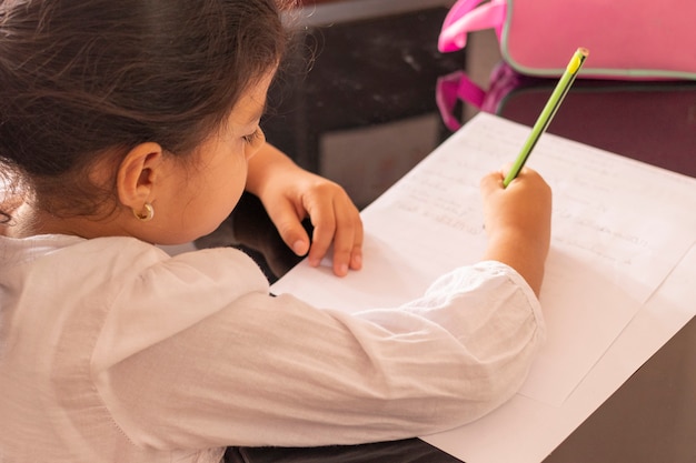 Foto niña está escribiendo en una mesa pequeña