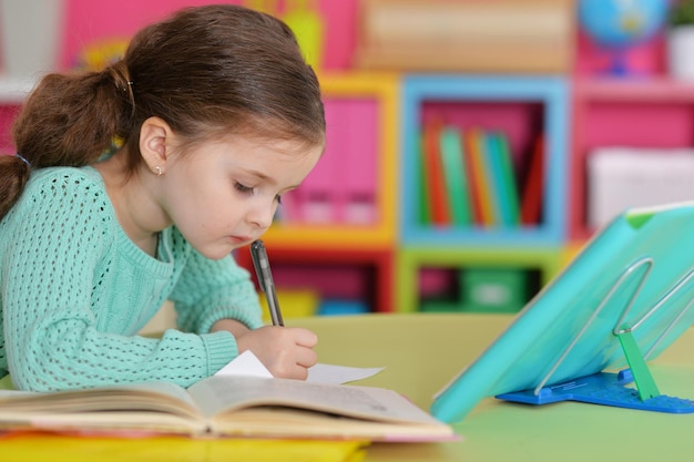 Niña escribiendo mientras está sentada en la mesa