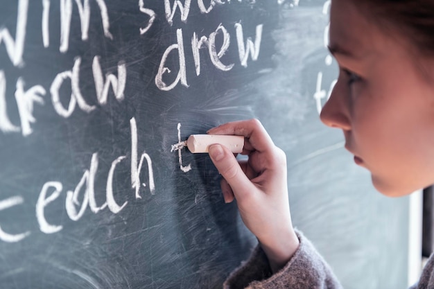 Foto niña escribiendo en la pizarra en el aula