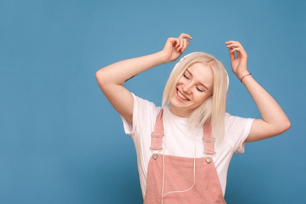 niña escucha música en auriculares con los ojos cerrados en azul