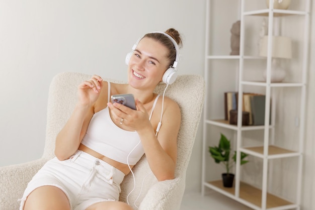 Niña escucha música en auriculares con teléfono en casa concepto de vacaciones de tiempo libre