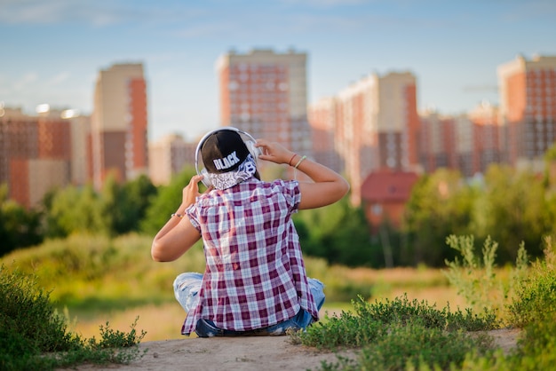 Niña escuchando música con auriculares, estilo urbano, estilo callejero al aire libre