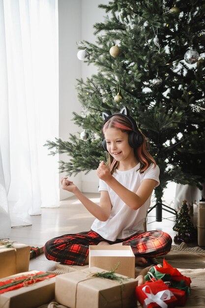 Foto niña escuchando música mientras desempaqueta regalos celebrando la navidad en casa