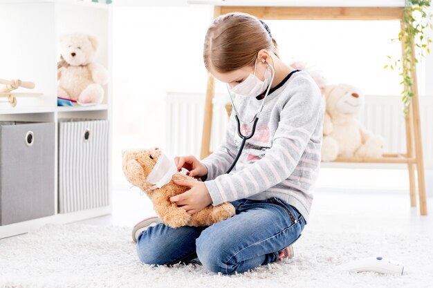 Niña escuchando por el oso de peluche estetoscopio, concepto médico