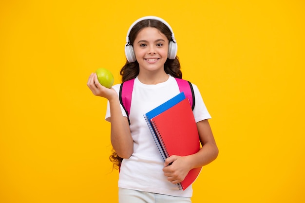 Niña de la escuela adolescente 12 13 14 años en auriculares y libros sobre fondo de estudio aislado