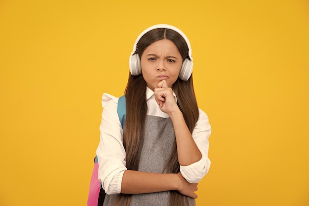 Niña de la escuela adolescente estudiante en auriculares sobre fondo amarillo estudio aislado Escuela de música