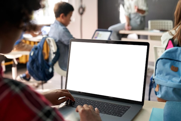 Foto niña de la escuela afroamericana que usa una computadora portátil con una pantalla de maqueta blanca