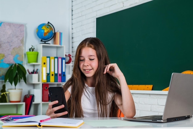 Niña en la escuela de aula con educación en línea para teléfonos inteligentes