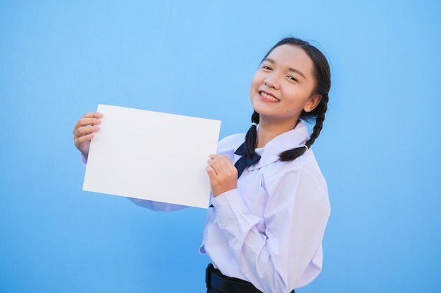 Niña de la escuela con cartelera sobre fondo azul.