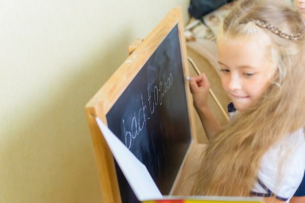 Niña de escuela caucásica divertirse en el pequeño escritorio