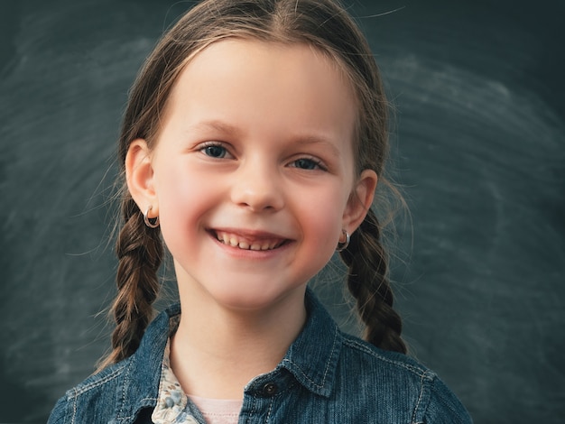 Foto niña de la escuela con coletas en pizarra