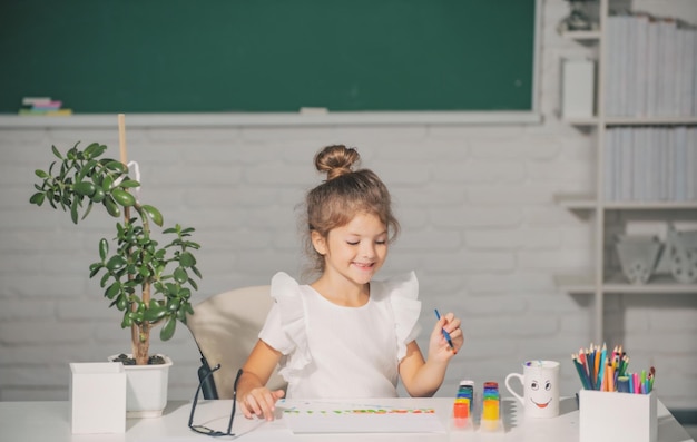 Niña en la escuela dibuja con pinturas Creatividad del artista infantil Cara divertida de los niños