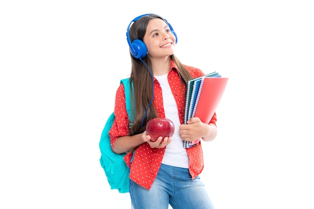 Niña de la escuela estudiante adolescente en auriculares sostienen libros sobre fondo blanco de estudio aislado