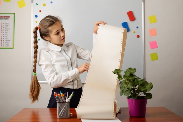 Niña de la escuela joven mirando una gran lista de cosas que hacer