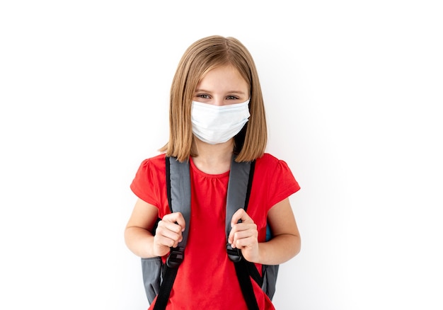 Niña de la escuela en mascarilla médica en blanco