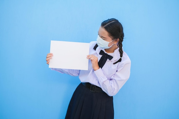 Niña de la escuela mostrar cartelera sobre fondo azul.