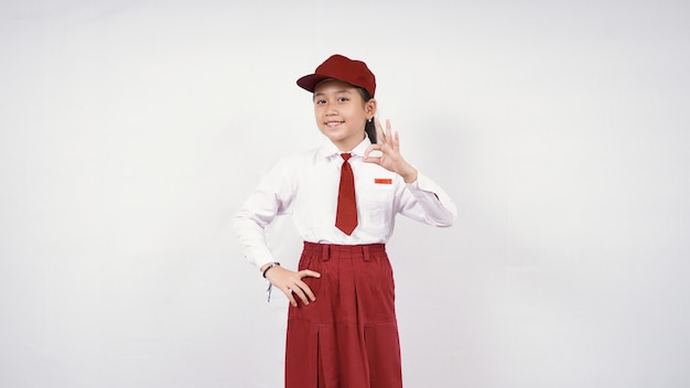 Niña de la escuela primaria asiática sonriente y bien aislada sobre fondo blanco