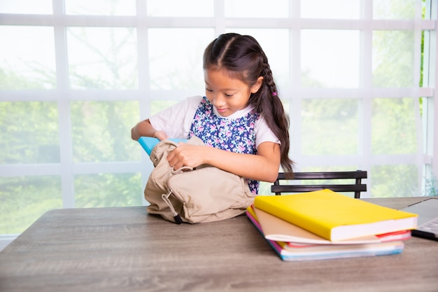 Niña de la escuela primaria empacando libros para las bolsas