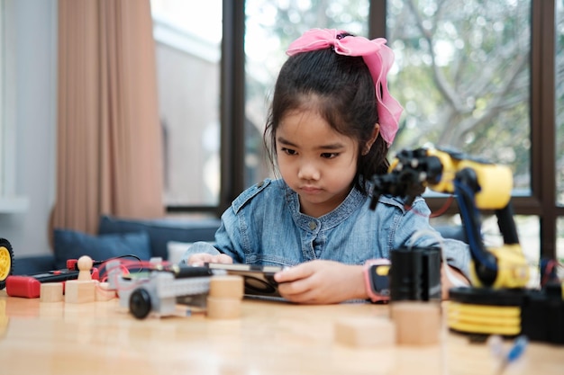 Niña de escuela primaria que usa una aplicación para controlar el coche en clase de STEM