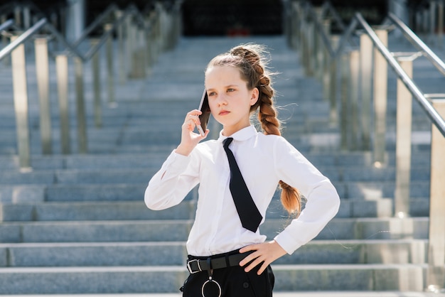 Niña de la escuela que habla por teléfono con un amigo