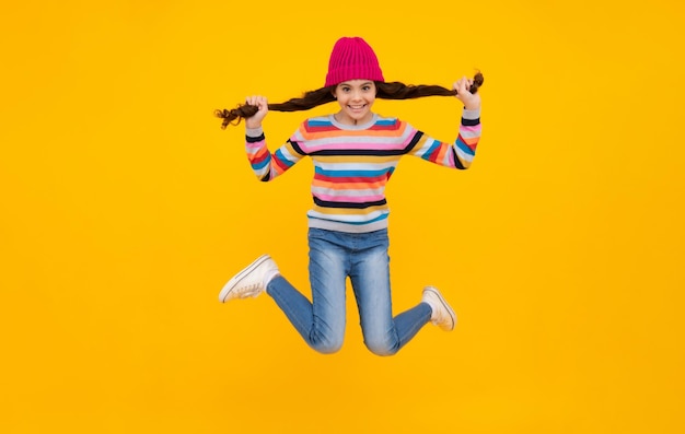 Niña de la escuela en ropa de invierno y sombrero cálido Vacaciones de invierno Modelo de moda infantil Saltar y correr Adolescente feliz emociones positivas y sonrientes de niña adolescente