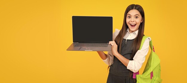 Niña de la escuela sostiene el cuaderno de la computadora portátil en el fondo del estudio aislado