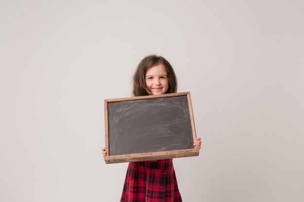 niña de la escuela con tablero de dibujo en blanco