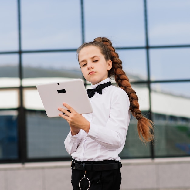 Niña de la escuela con tableta fuera