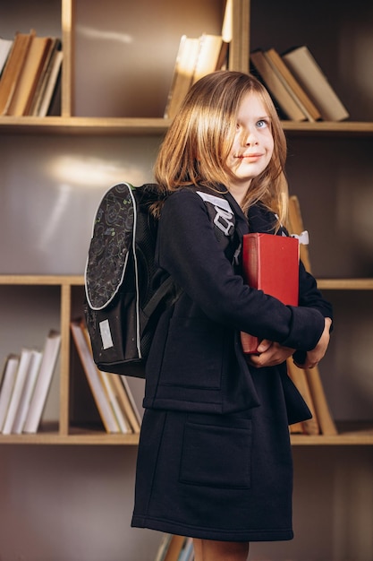 Niña de la escuela en uniforme en la biblioteca