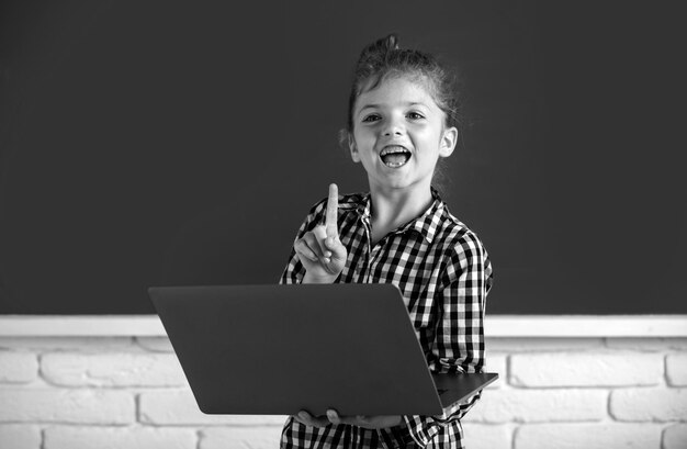 Niña de la escuela usando una computadora portátil digital en clase retrato de un alumno divertido de estudio de escuela primaria