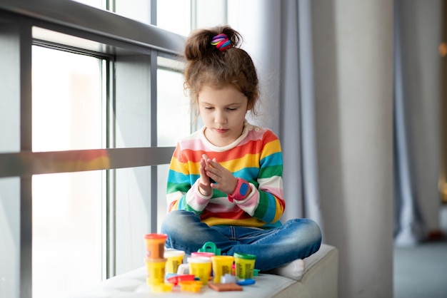 Una niña esculpe de plastilina.