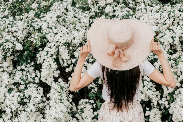 Niña de espaldas en un sombrero de flores blancas